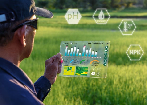 A farmer analyzing crop data on a transparent digital tablet with augmented reality elements, displaying pH, humidity, temperature, and nutrient levels in a green field