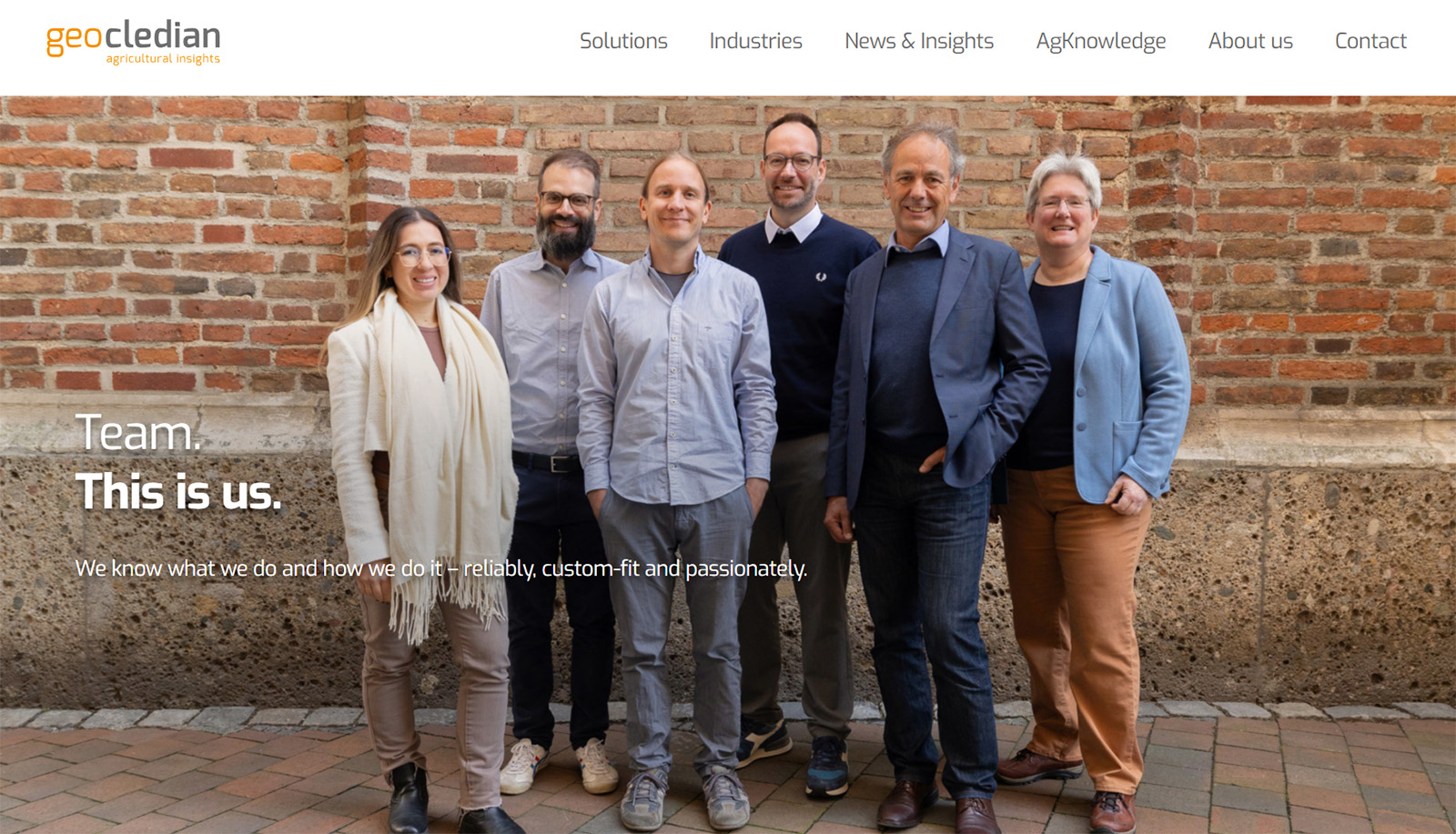 Group photo of the Geocledian team standing in front of a brick wall, showcasing their expertise in agricultural insights and digital solutions.